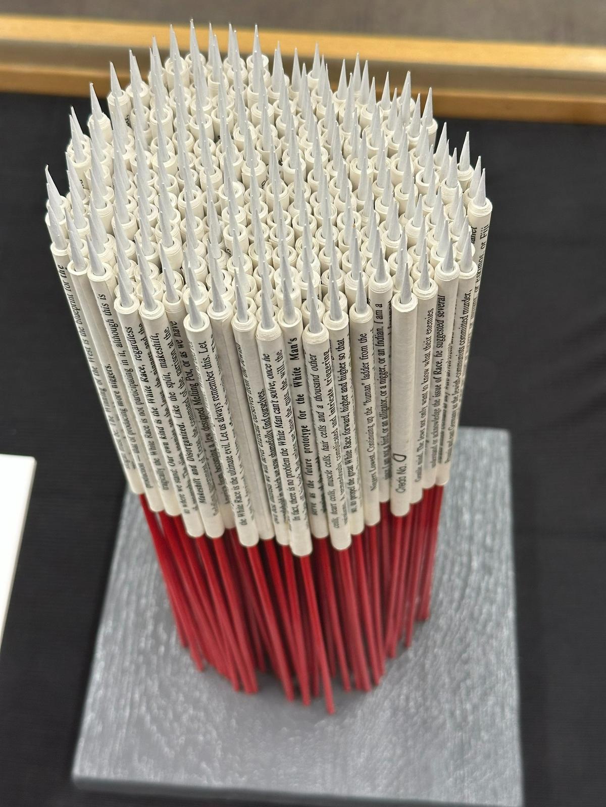Ryan Sarah Murphy, of New York, created Take Heed and Tremble, which pairs the torn pages of “The White Man’s Bible” with 12-inch wooden skewers, suggesting a dangerous cluster of bottle rockets, minus any indication of a fuse, rendering them inert and ineffective.