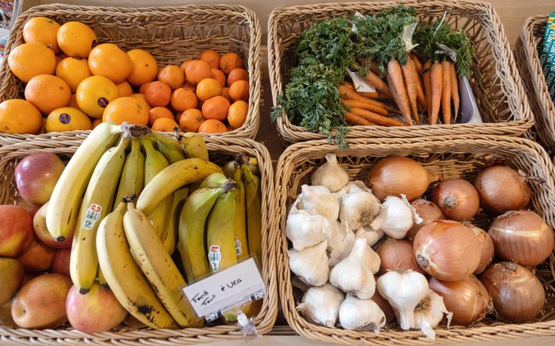 Produce for sale includes bananas, oranges, apples, onions and garlic.