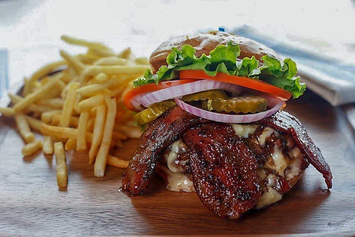 The Bacon Bacon Burger ($13.49) is two four-ounce signature patties stuffed full of house pork belly bacon, topped with bacon jam and melted sharp cheddar cheese, served on a toasted brioche bun with lettuce, pickle, tomato, onion and Hog Sauce.