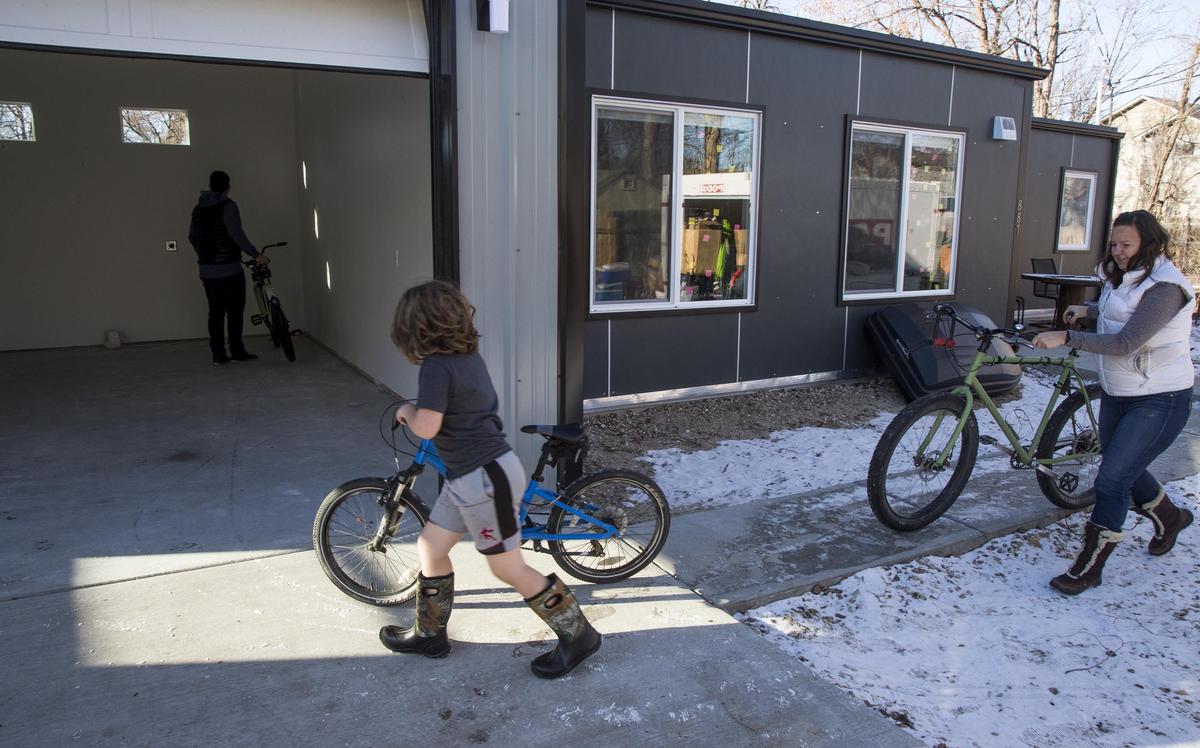 Raleigh Lynam, 6, and his mother, Jo Burgoon, start moving belongings into the garage of the container home. An additional container dwelling, on the same lot behind the noncontainer two-car garage, is being rented to a friend.