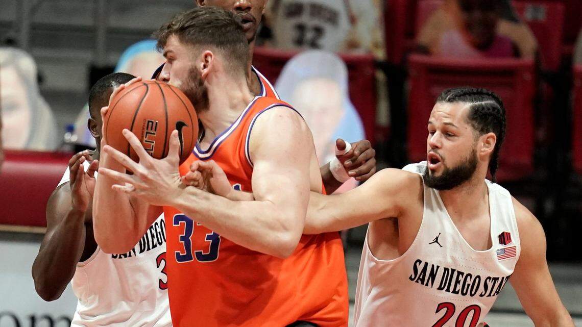 Boise State forward Mladen Armus, center, fights to hang onto the basketball against San Diego State guard Jordan Schakel, right, during the first half of their game Saturday in San Diego. SDSU won 62-58.