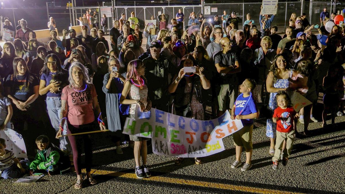 Hundreds of family and friends, holding welcome- home posters, await the arrival of troops from the Idaho Air National Guard at Gowen Field.