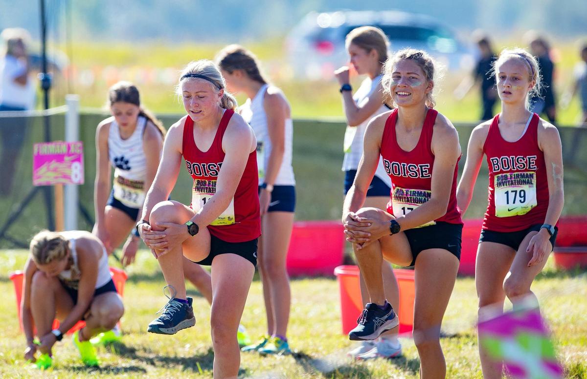 Boise’s Sammy Smith, left, and Allie Bruce, center, stretch before the elite cross country race at the Bob Firman Invitational in September.