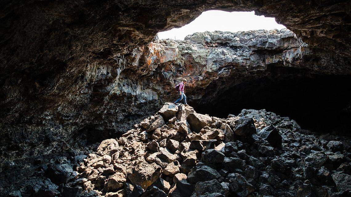 A visitor is shown exploring Indian Tunnel Cave