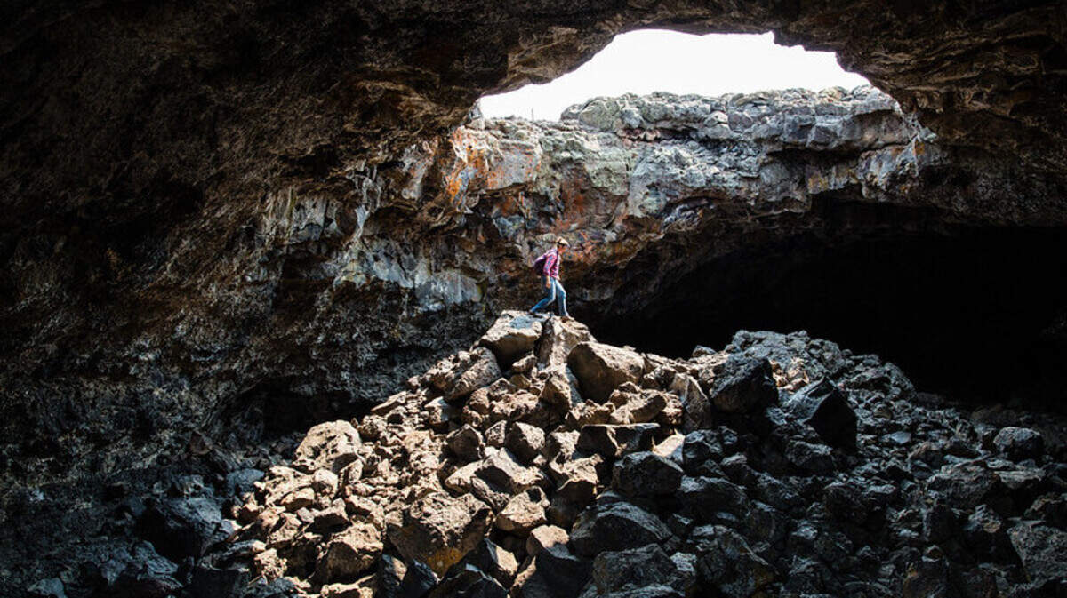 A visitor is shown exploring Indian Tunnel Cave