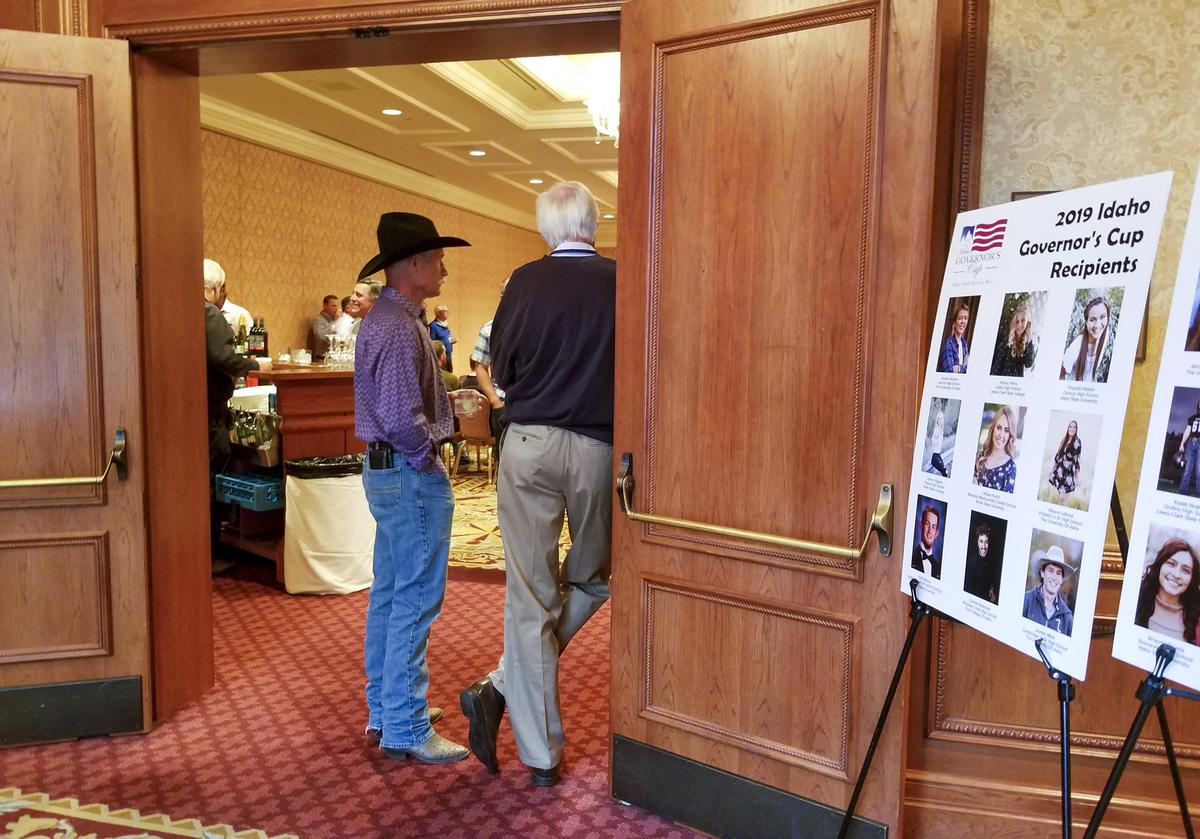 Doug Sayer, chairman of the Idaho Governor’s Cup, left, watches as the cup’s 2019 golf tournament winners claim their awards. Arlen Wittrock, right, is a lobbyist who introduced Sayer to the event years ago. Outside the door, poster boards introduced the year’s scholarship recipients to donors.