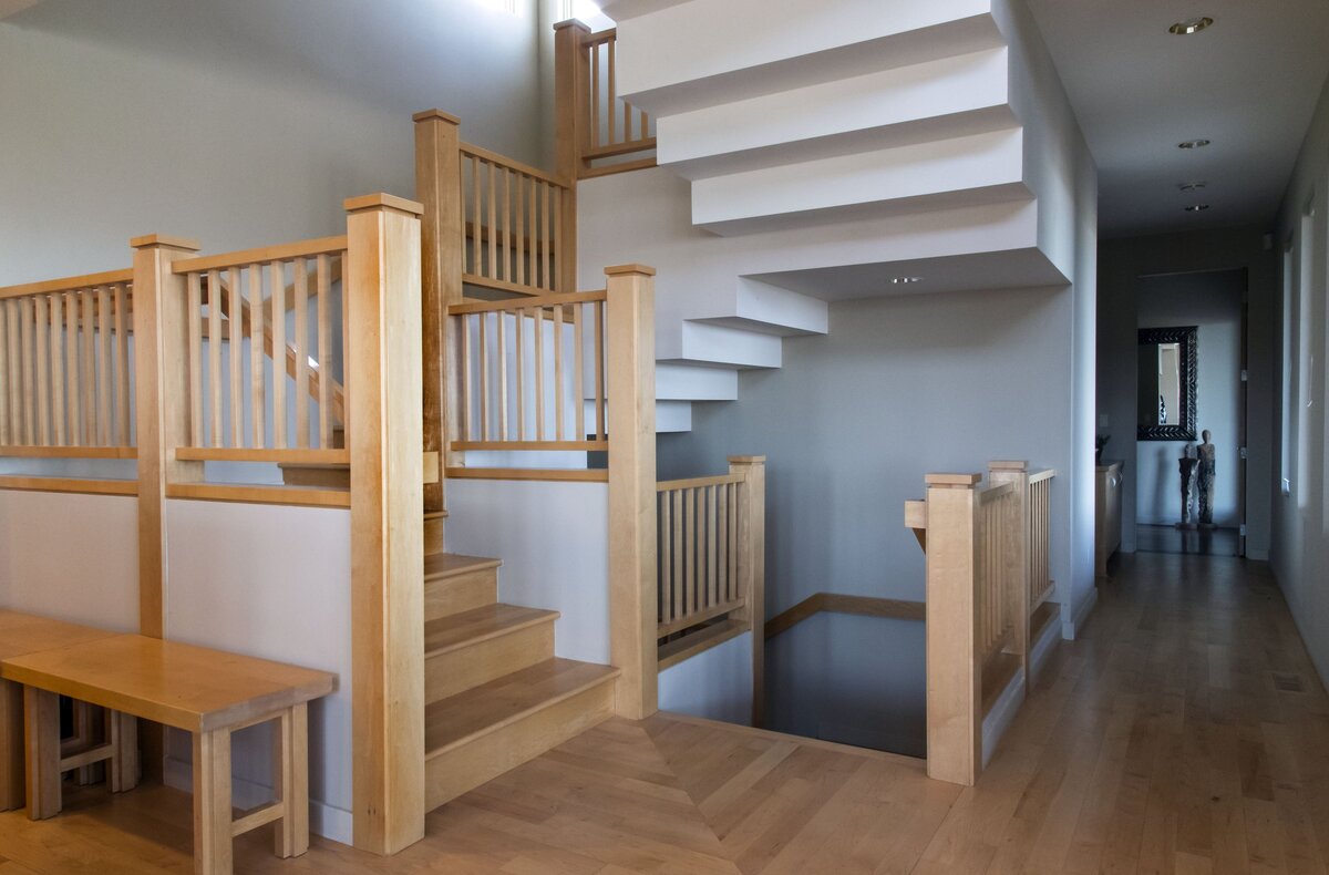 A central, wooden staircase connects three levels of the L-shaped Satz home.