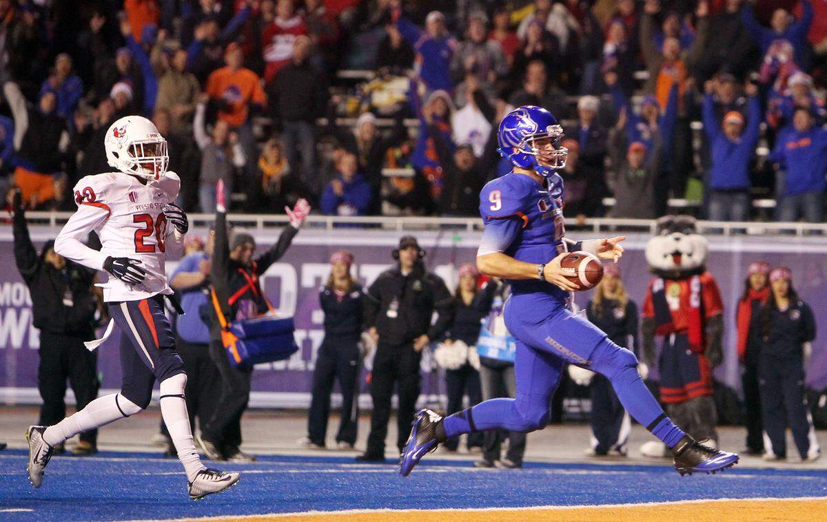 Former Boise State quarterback Grant Hedrick scores a touchdown ahead of Fresno State defensive back Malcolm Washington in the 2014 Mountain West championship game at Albertsons Stadium. 