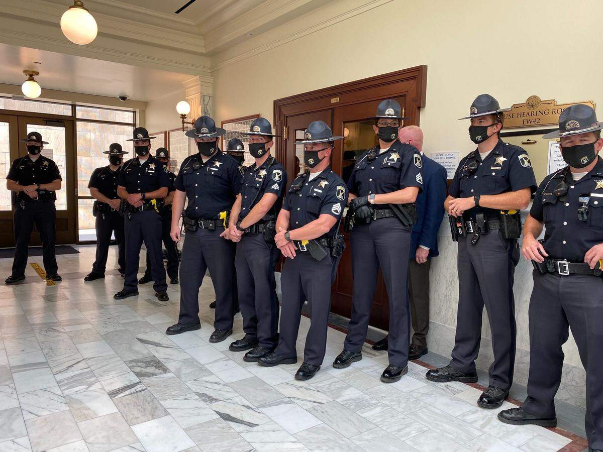 Idaho State Police troopers stand guard outside the hearing room where the rescheduled Judiciary, Rules and Administration Committee meeting was taking place Tuesday afternoon.