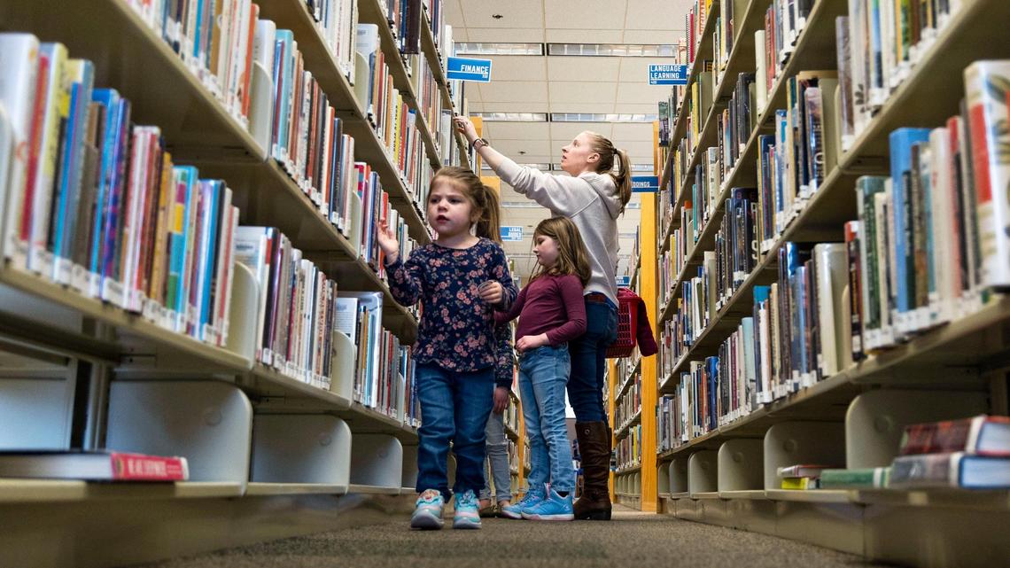 Four-year-old Makenna Kitzmiller walks along a row of books as her mother, Rachel Kitzmiller, looks for a book title at a Meridian library. Lawmakers Wednesday debated whether “harmful” books are readily available to children at the state’s libraries.