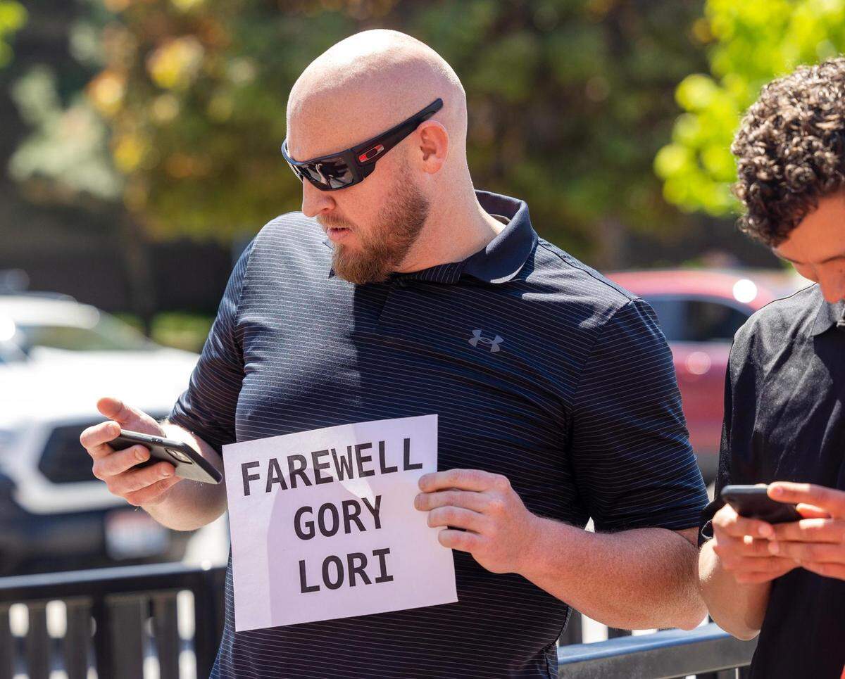 Daniel Fitt of Rexburg, left, holds a sign and his cellphone to listen to a livestream of the verdict Friday outside of the Ada County Courthouse in Boise.