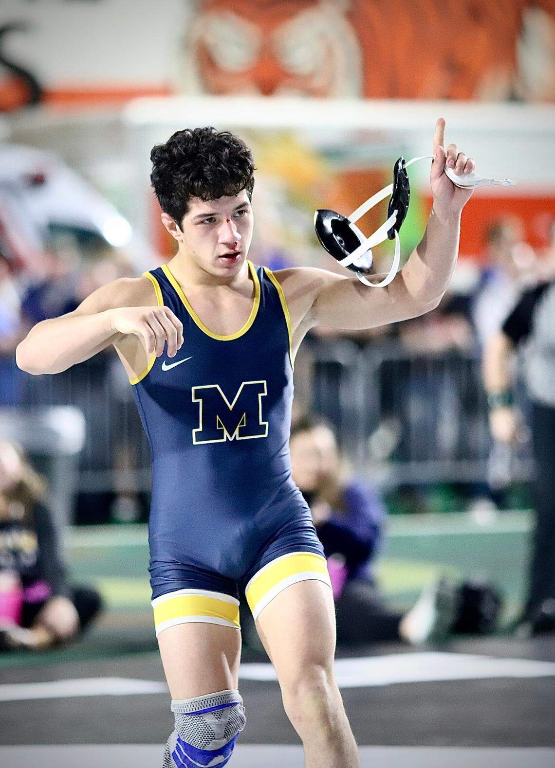 Meridian’s Jerimiah Gonzalez flashes a No. 1 to the fans Saturday following his 5A 113-pound state championship win over Nampa’s Vincent Contreras.