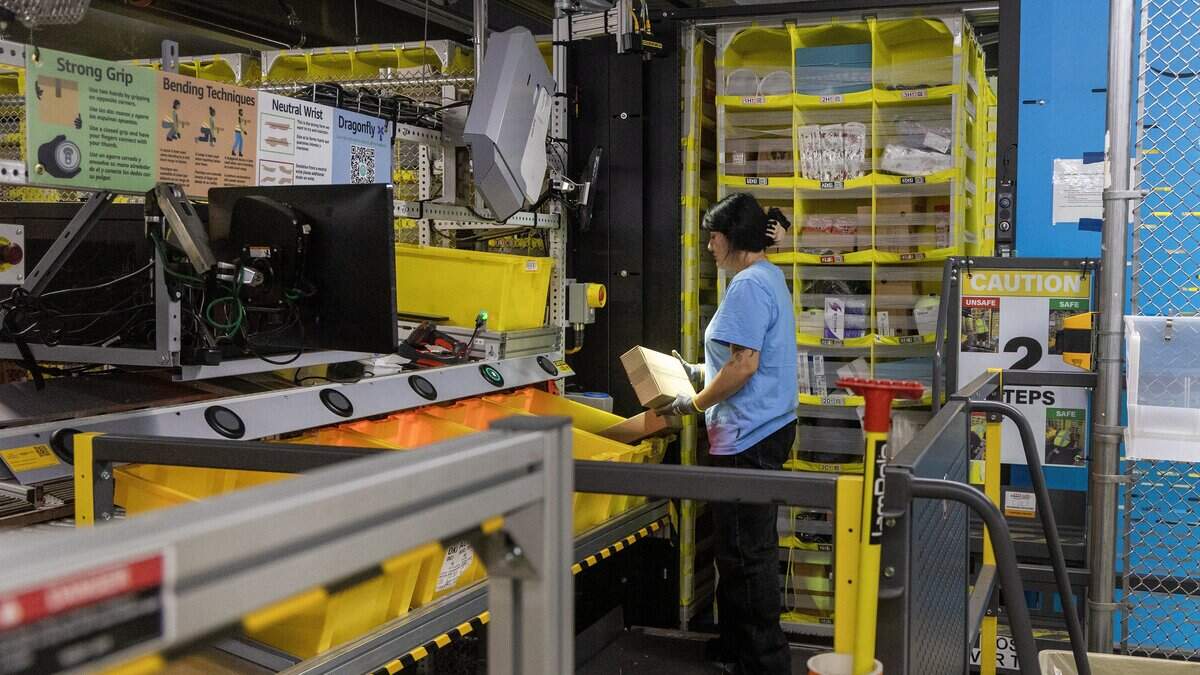 An Amazon associate grabs inventory of ordered items from a robotic shelf at the Nampa Fulfillment Center, Thursday, June 25, 2026.