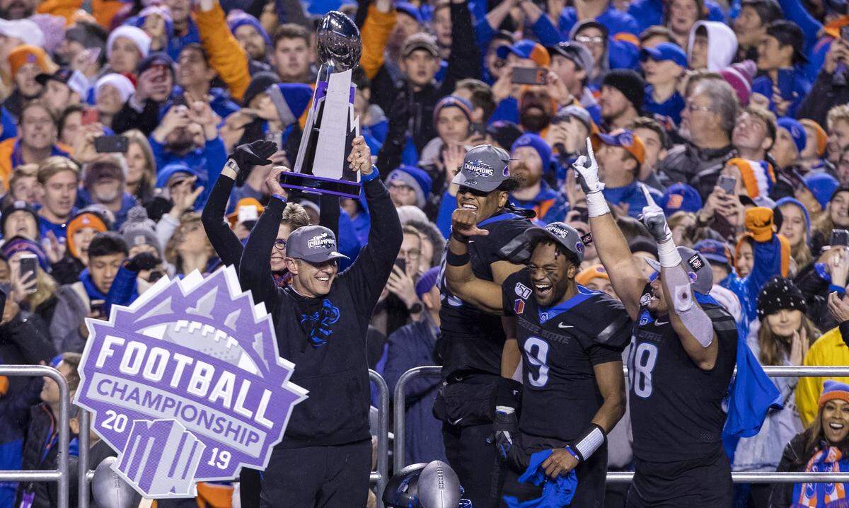Former Boise State football coach Bryan Harsin holds the Mountain West Conference championship trophy with offensive and defensive MVPs Jaylon Henderson and Sonatane Lui following the 31-10 win over Hawaii.