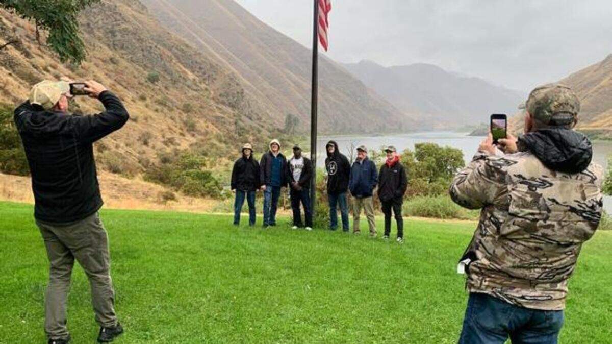 USS Idaho submariners pose for photos near the American flag at Cache Creek Ranch in Hells Canyon on Thursday. The Navy sailors spent the past week exploring the Gem State.