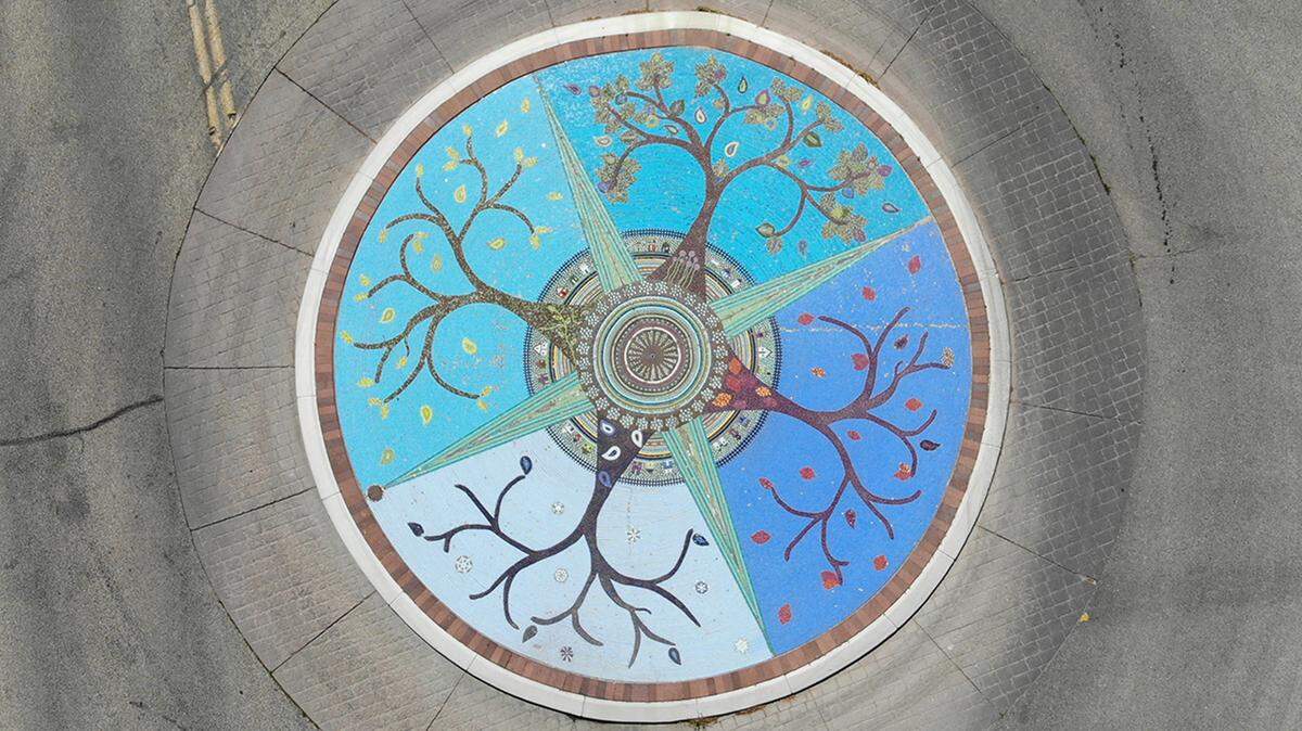 The mosaic on Crescent Rim Drive near the Boise Depot contains more than 300,000 tiles. Its imagery reflects the depot and travel. The design includes rail spikes that form a central sunburst, a cross-section of track, compass points and miniature houses. Trees, one for each season, represent Boise as the City of Trees and the Bench’s historic identity as a place of farms and orchards.