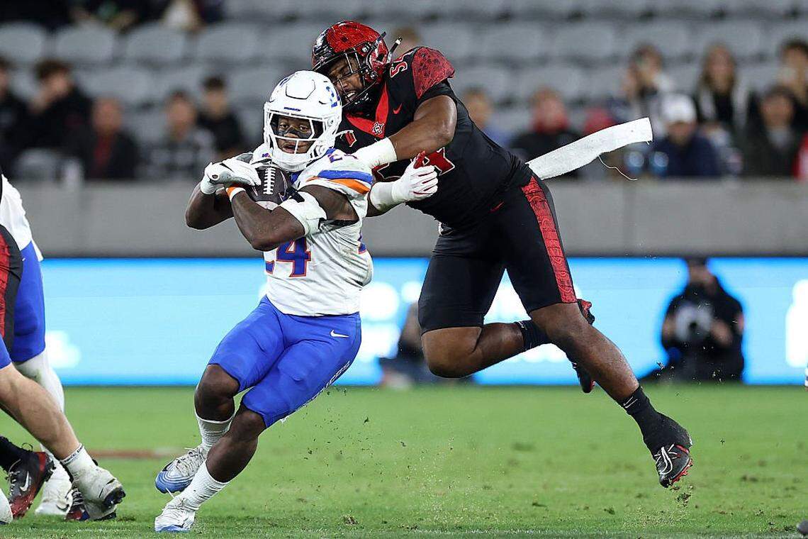 SAN DIEGO, CALIFORNIA - NOVEMBER 15: Krishna Clay #54 of the San Diego State Aztecs tackles Dylan Riley #24 of the Boise State Broncos during the first half of a game at Snapdragon Stadium on November 15, 2025 in San Diego, California. (Photo by Sean M. Haffey/Getty Images)