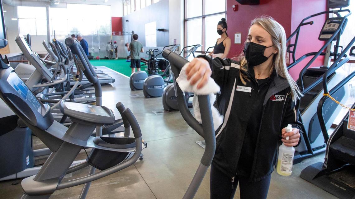 Sydney Komlenic, operations manager at Axiom Fitness on Parkcenter Boulevard in Boise, joins the entire staff in cleaning exercise equipment during the coronavirus pandemic.