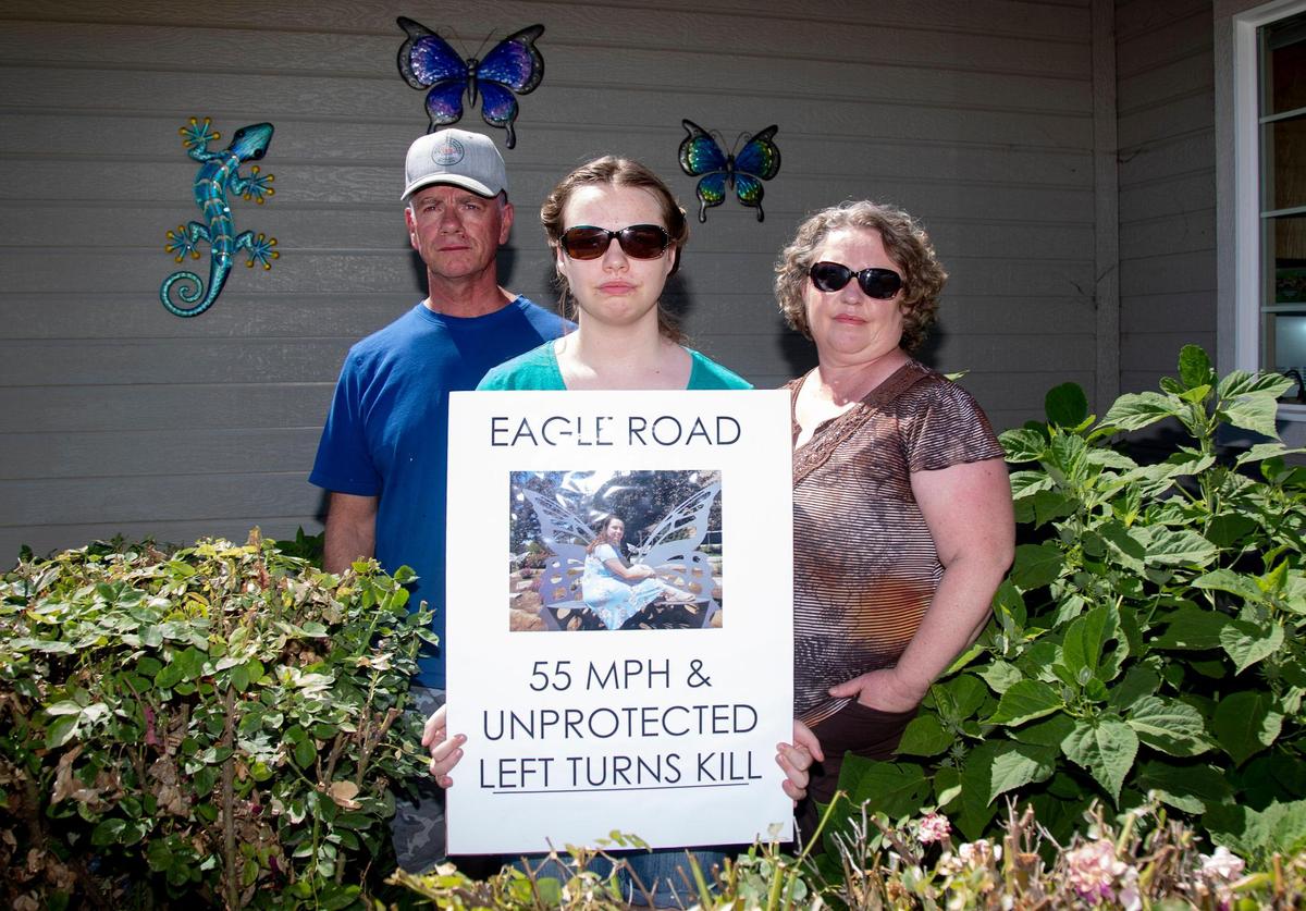 Tristen Boesch, center, holds a sign with a photo of her sister, Kess Boesch, who died in a car crash on Eagle Road in 2021. Boesch’s parents, Laurie, left, and Jerry, right, say the speed limit on Eagle Road needs to be lowered, and unprotected left turns should be banned.