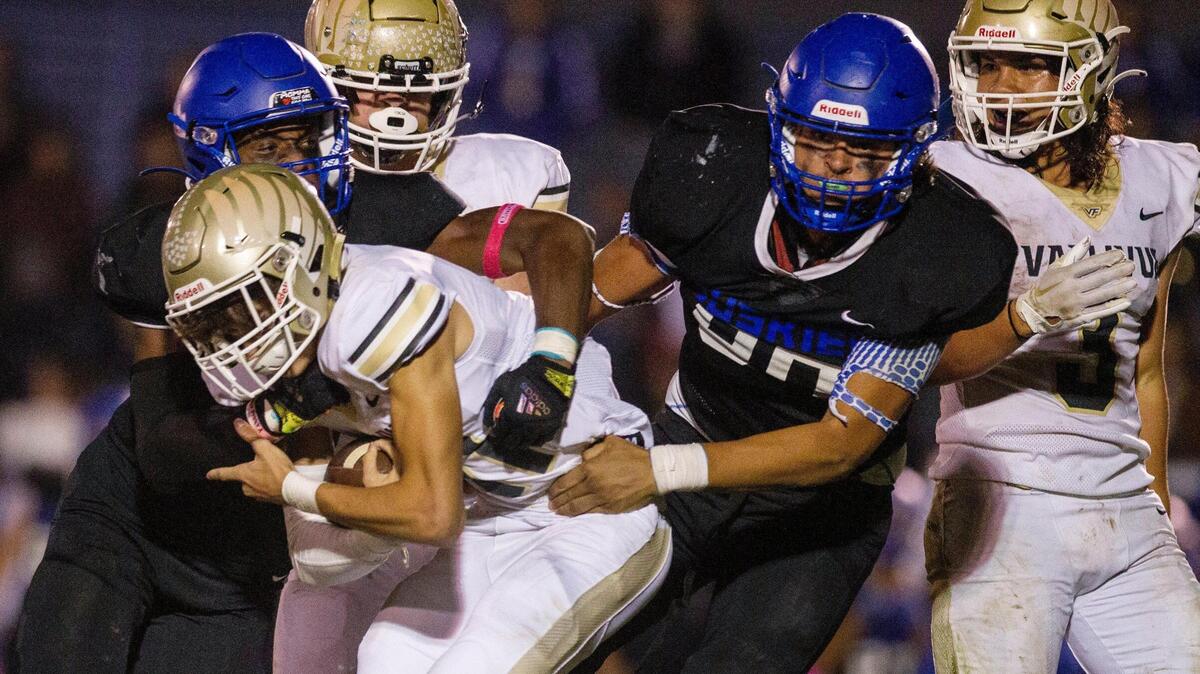Emmett defenders Lucas Briscoe, left, and Cristian Sanchez, right, combine to drop Vallivue quarterback Isaac Moore on Friday. Emmett rallied for a 21-20 win to clinch a 4A state playoff berth.