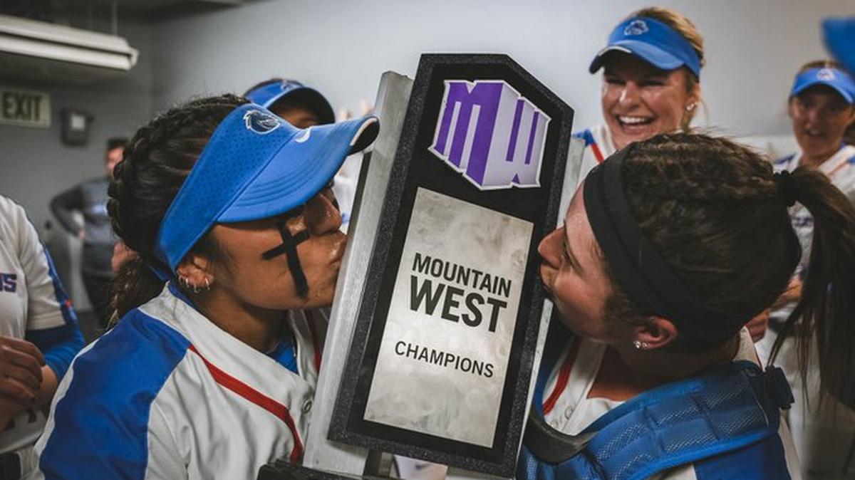 Boise State softball players Eliyah Flores, left, and Serena Huchingson kiss the Mountain West trophy after a 3-0 win at Fresno State on Friday clinched the regular season championship.