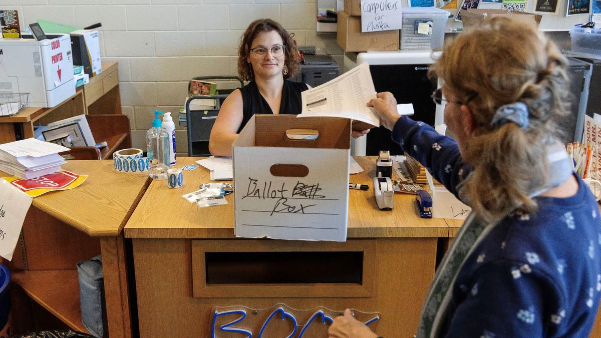Volunteer Chrystal Allen, left, collects ballots from people voting in the Idaho Democratic presidential caucus at Timberline High School in Boise, Thursday.