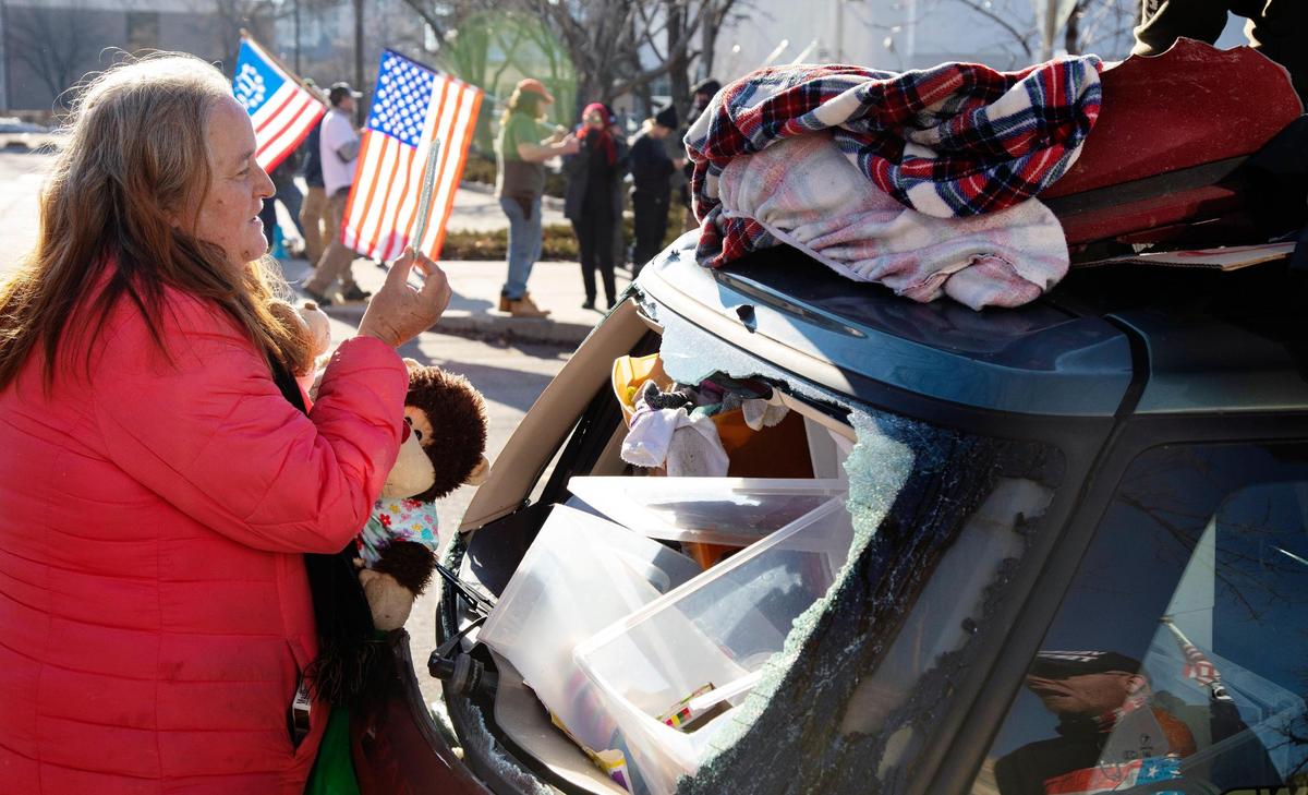 SherryJo Crandall pulls out a piece of her broken windshield from the back of her car that was hit on the road while she was sleeping on it early Saturday morning. Her destroyed car was parked in the middle of the homeless protest and counter protest by Idaho Liberty Dogs. Crandall lost her housing last November.