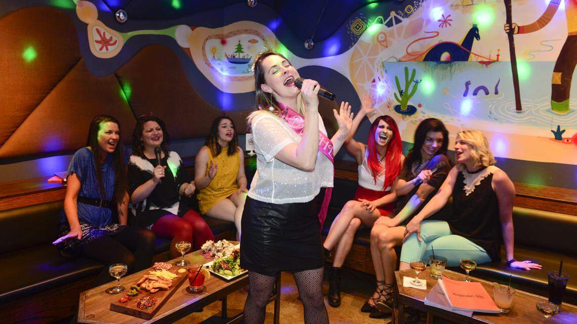 A woman sings while her friends join in inside a private suite at Voicebox.