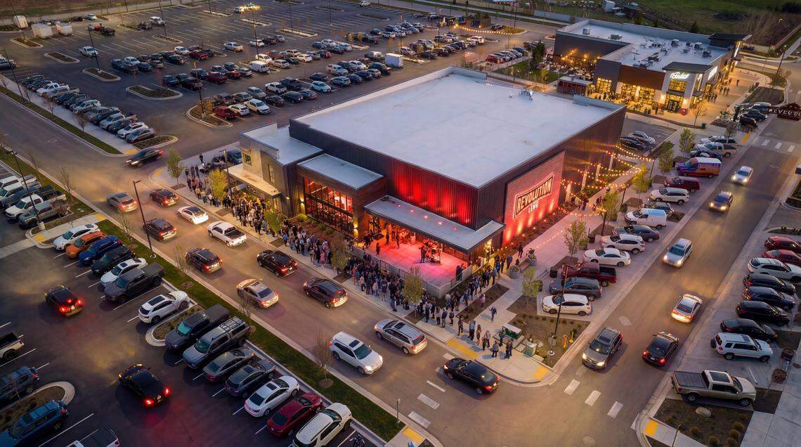 An architectural rendering of the planned Revolution Concert House lit up with crowds at night.