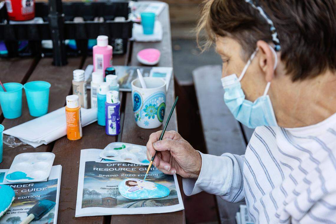 Interfaith Sanctuary resident Sherri paints an image of an angel on a rock as part of a memorial project for a fellow resident at the homeless shelter who was unvaccinated and died from COVID-19.