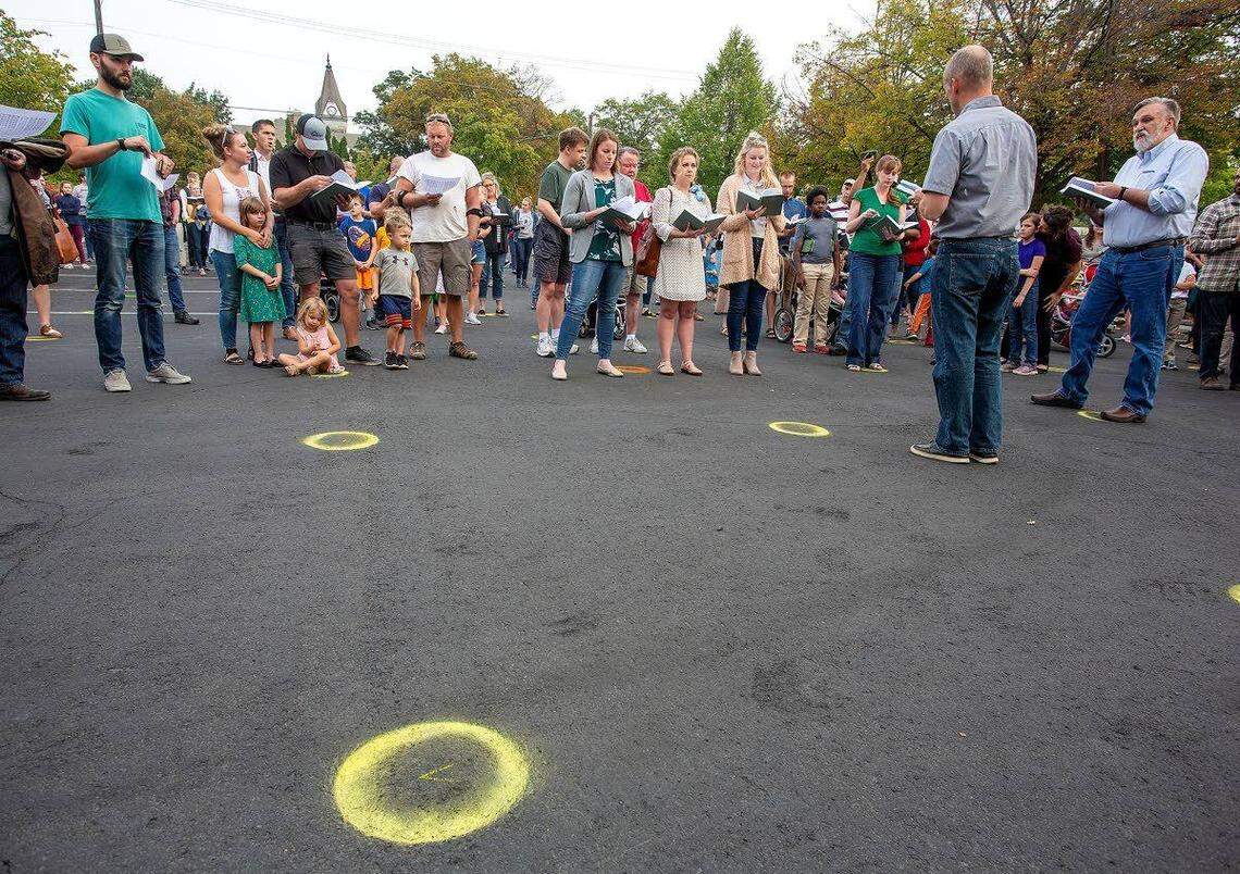 Christ Church Pastor Doug Wilson, right, sings with church members Wednesday night outside Moscow City Hall. The city painted circles on the parking lot so that people could socially distance. They didn’t.