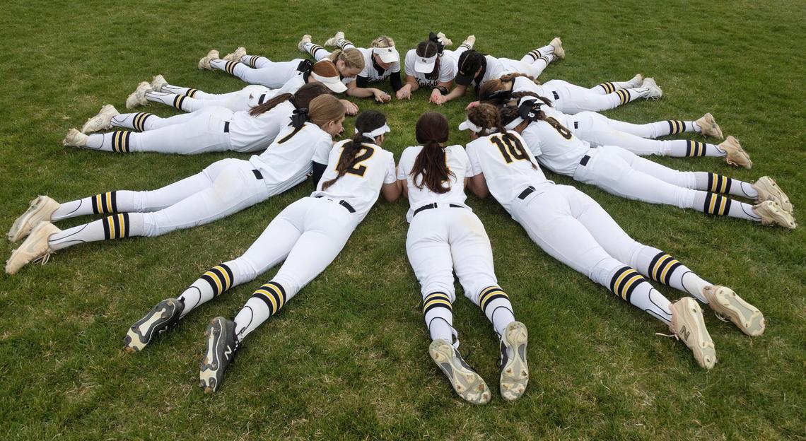 The Bishop Kelly softball team links hands in a circle on the field in a prayer before the start of their game at home against Vallivue on Tuesday.