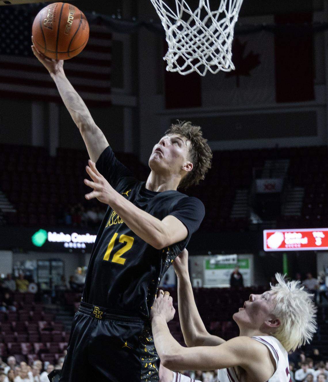Bishop Kelly guard Conor Goss scores in the paint defended by Columbia's Easton Lott in the 5A District Three boys basketball championship game at Idaho Central Arena in downtown Boise, Friday, Feb. 27, 2026.