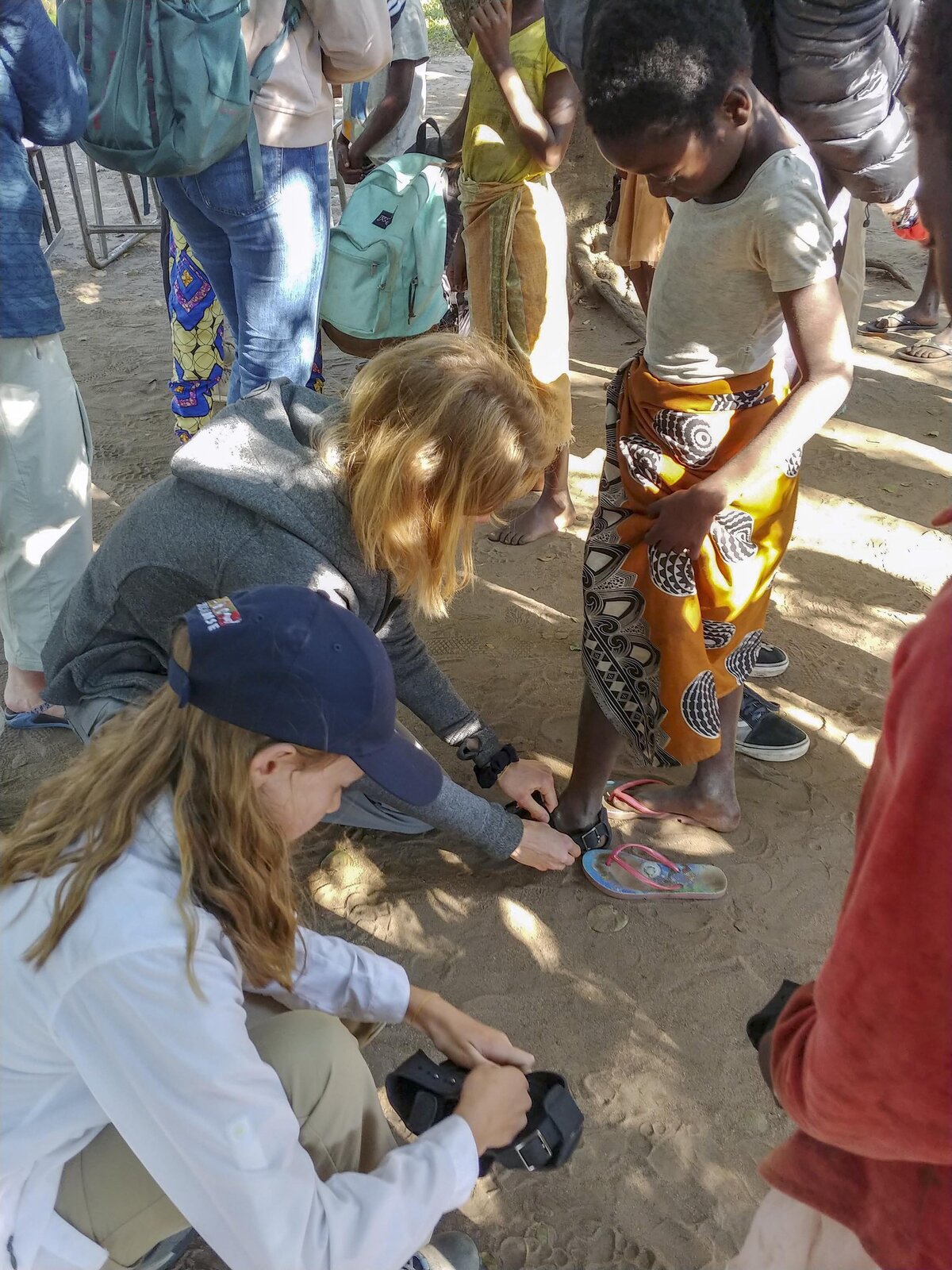 Boise girls place shoes donated by the Rotary Club on the feet of girls from the village of Nhanbita just outside of Gorongosa National Park.