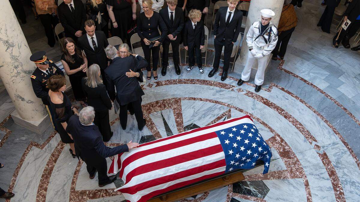 Following a ceremony honoring former Idaho Gov. Dirk Kempthorne, current Gov. Brad Little gives Patricia Kempthorne a hug near the casket in the Idaho State Capitol rotunda, Friday, May 15, 2026.