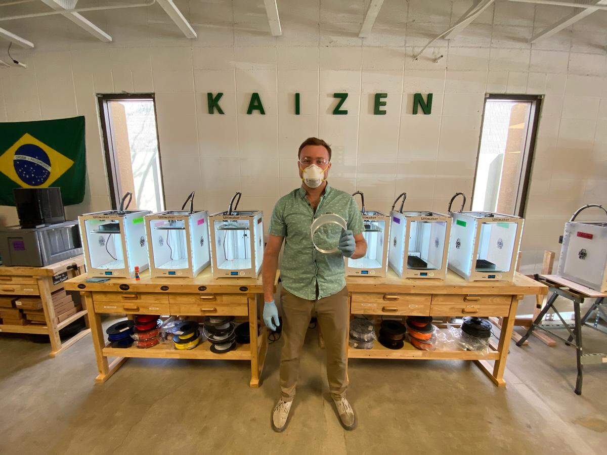 Justin Shook shows off the headband prototype he printed at his workshop in Boise as part of The Face Shield Initiative. Behind him, a sign on the wall reads “kaizen,” a Japanese word that loosely translates to “continuous improvement.”