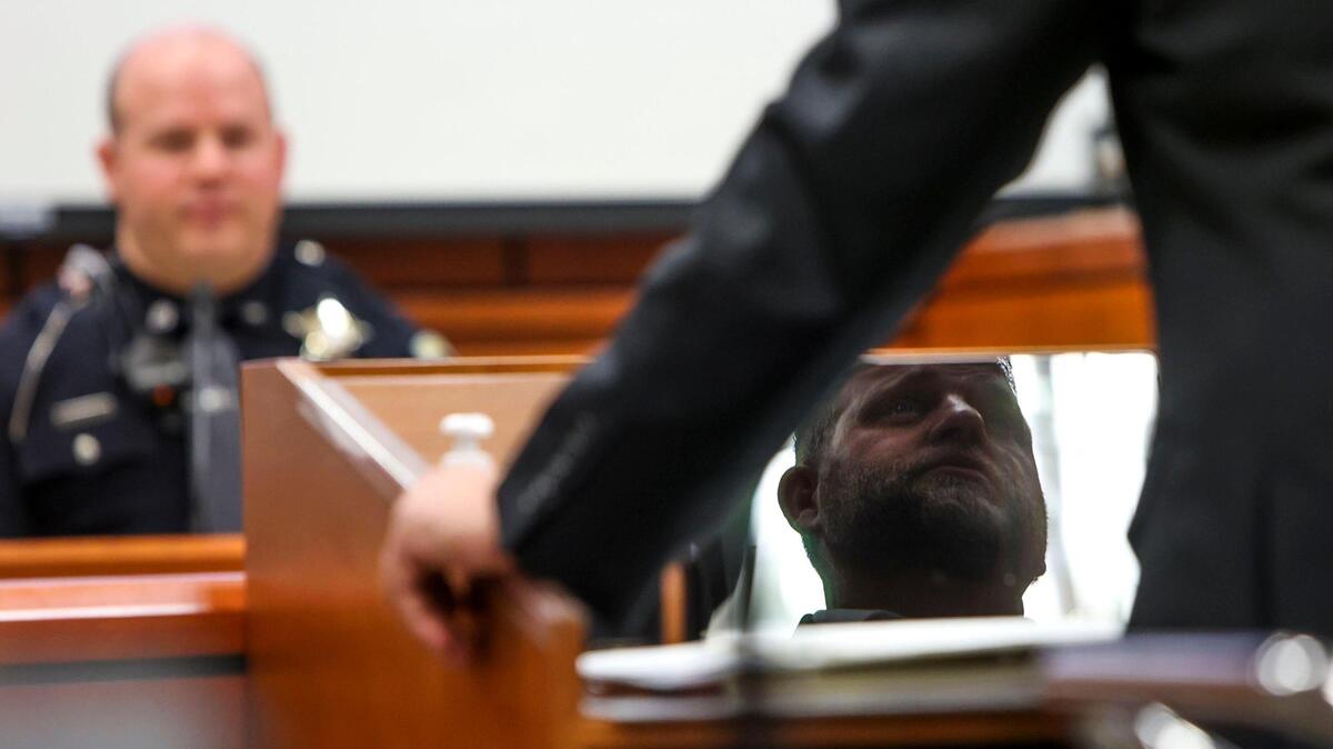 Ammon Bundy’s face can be seen in a reflection when he defended himself against trespassing charges in March 2022.