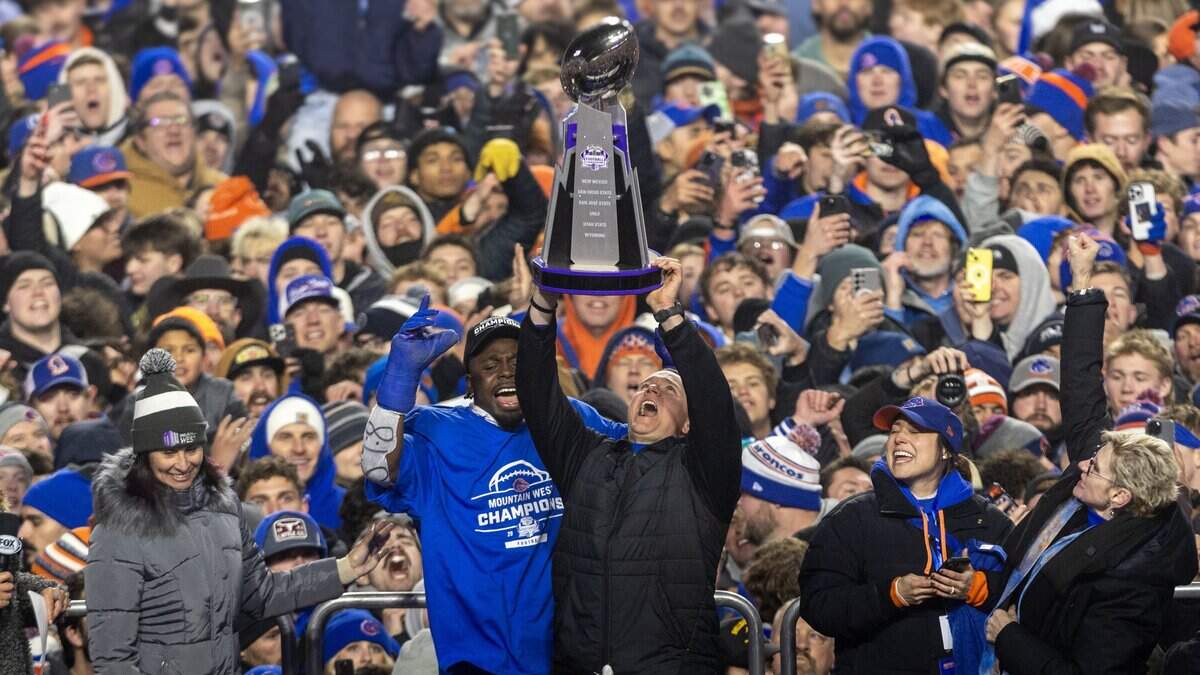 Boise State head coach Spencer Danielson holds up the Mountain West championship trophy with former Bronco safety Seyi Oladipo at his side after defeating UNLV 21-7 at Albertsons Stadium in December 2024.