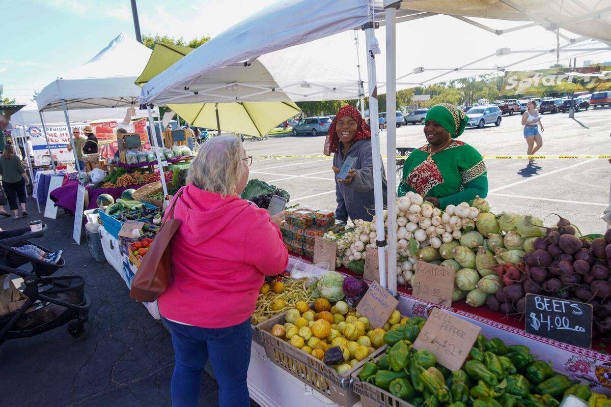 Customers shop at the Safari Farms booth at Boise Farmers Market.