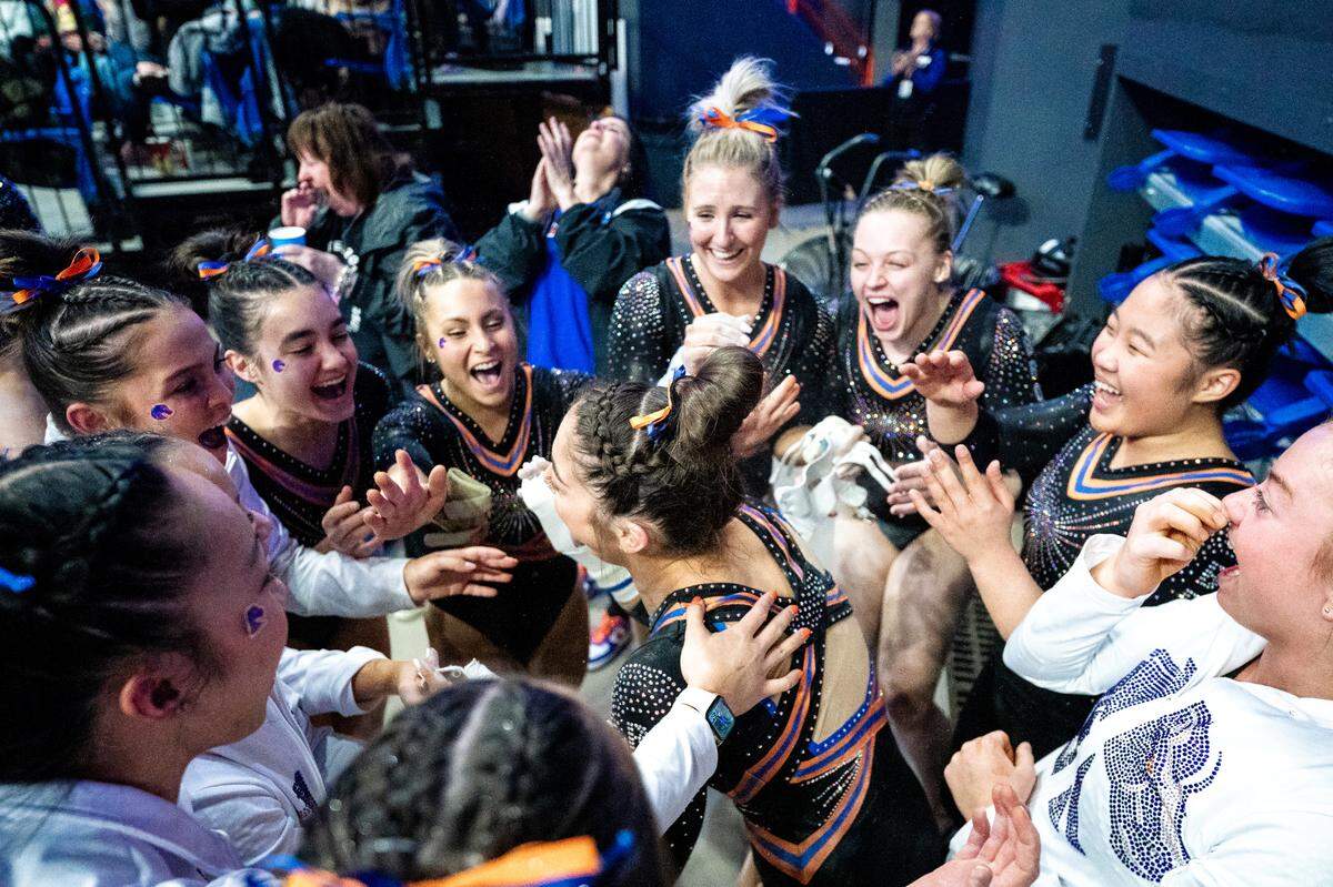 Boise State gymnast Emily Lopez is swarmed by teammates after her perfect score in bars was announced during a meet against BYU on Feb. 17.