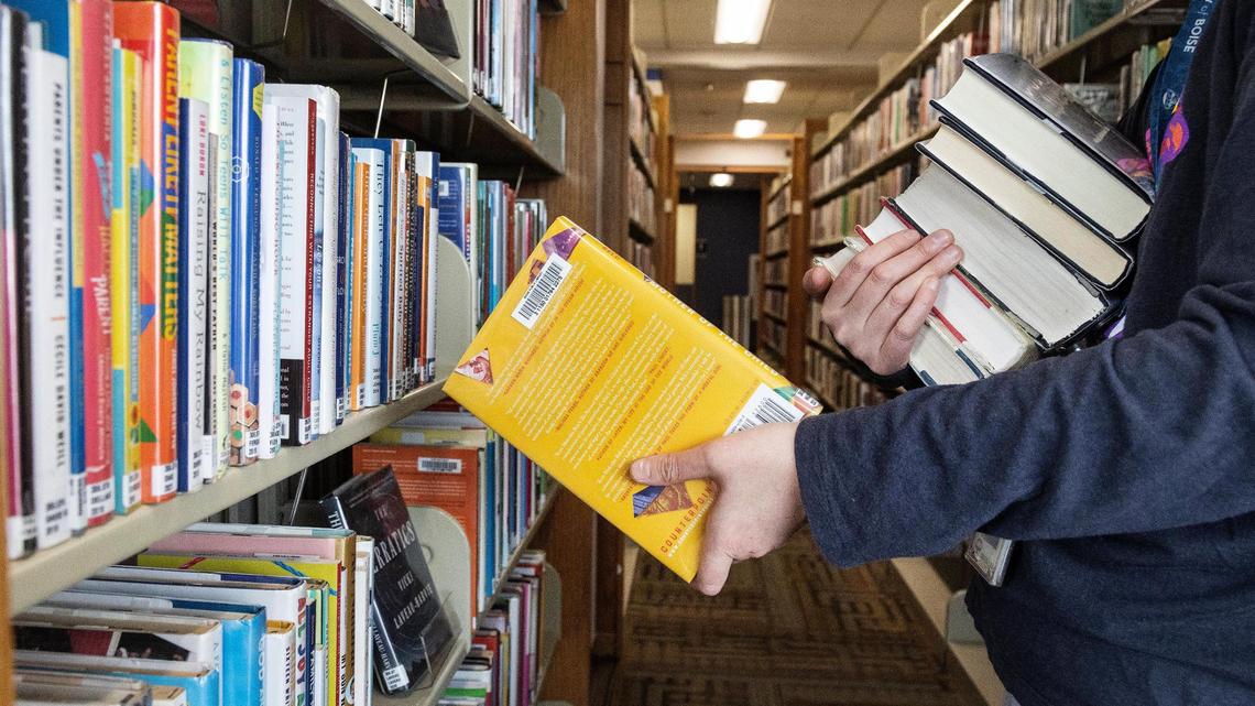 A librarian returns books to the shelves at a Boise Public Library branch on Tuesday. Idaho lawmakers on Wednesday considered competing bills meant to address children’s access to “harmful” material in libraries.