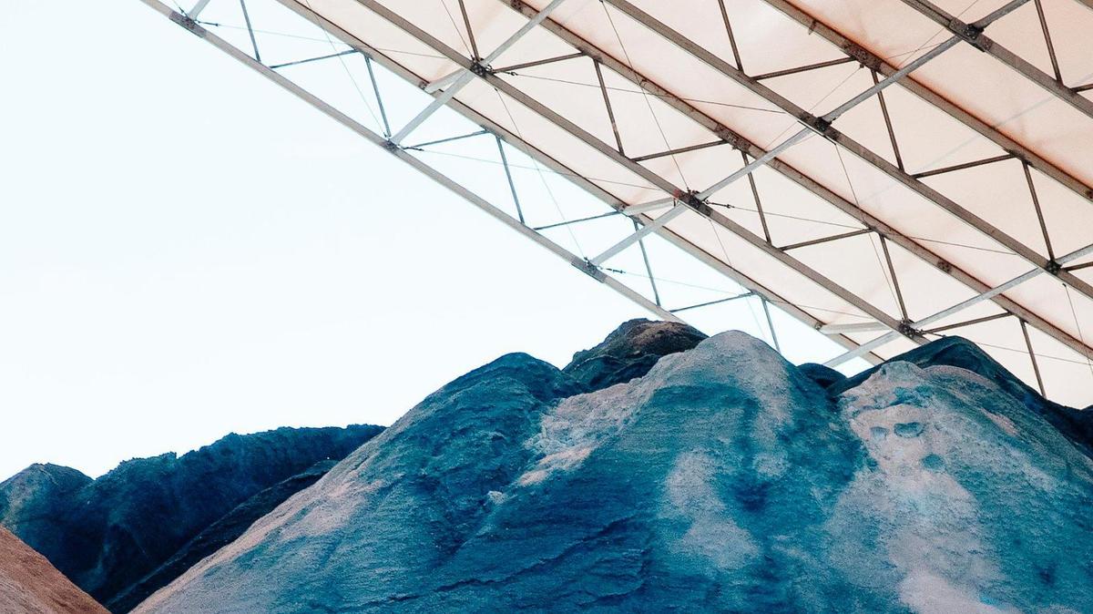 A pile of sand and blue salt sit under a canopy, viewed from close to the blue salt.
