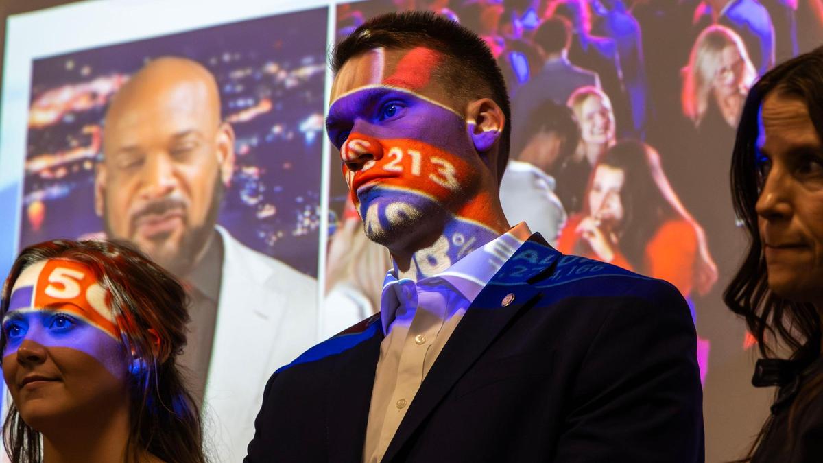 With his face painted by a election night results projected on a background screen, Ben Fulcher, son of U.S. Congressman Russ Fulcher, R-Idaho, listens to his father thank Idaho Republicans for re-electing him into office.