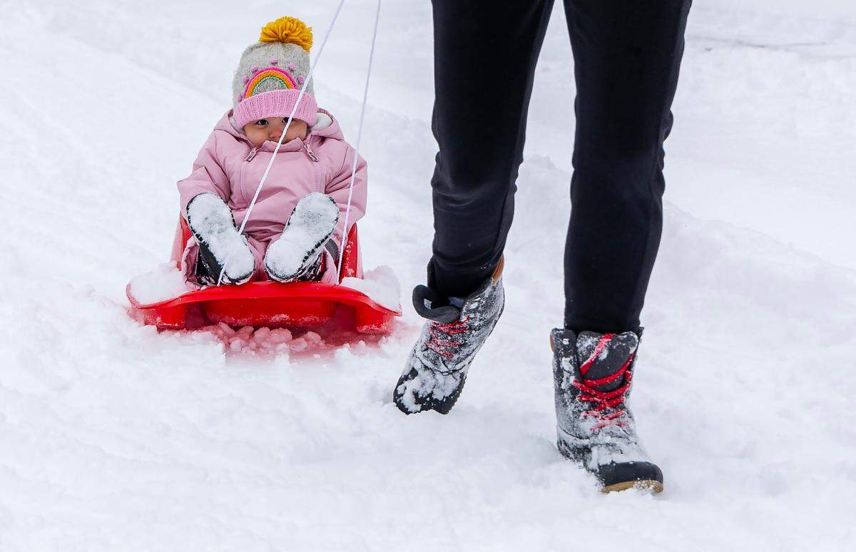 Monica Ahmetovic pulls her daughter Izabel, 1, in a sled through the snow on their street in Meridian.