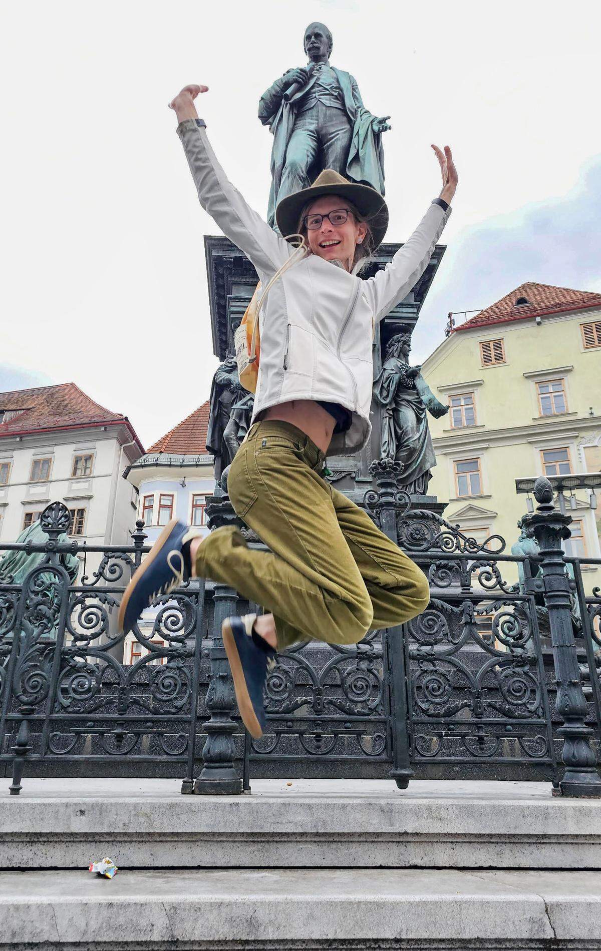 Cassidy Robertson jumps in front of a statue in the main square of Graz, Austria, where she resides, in April 2025.