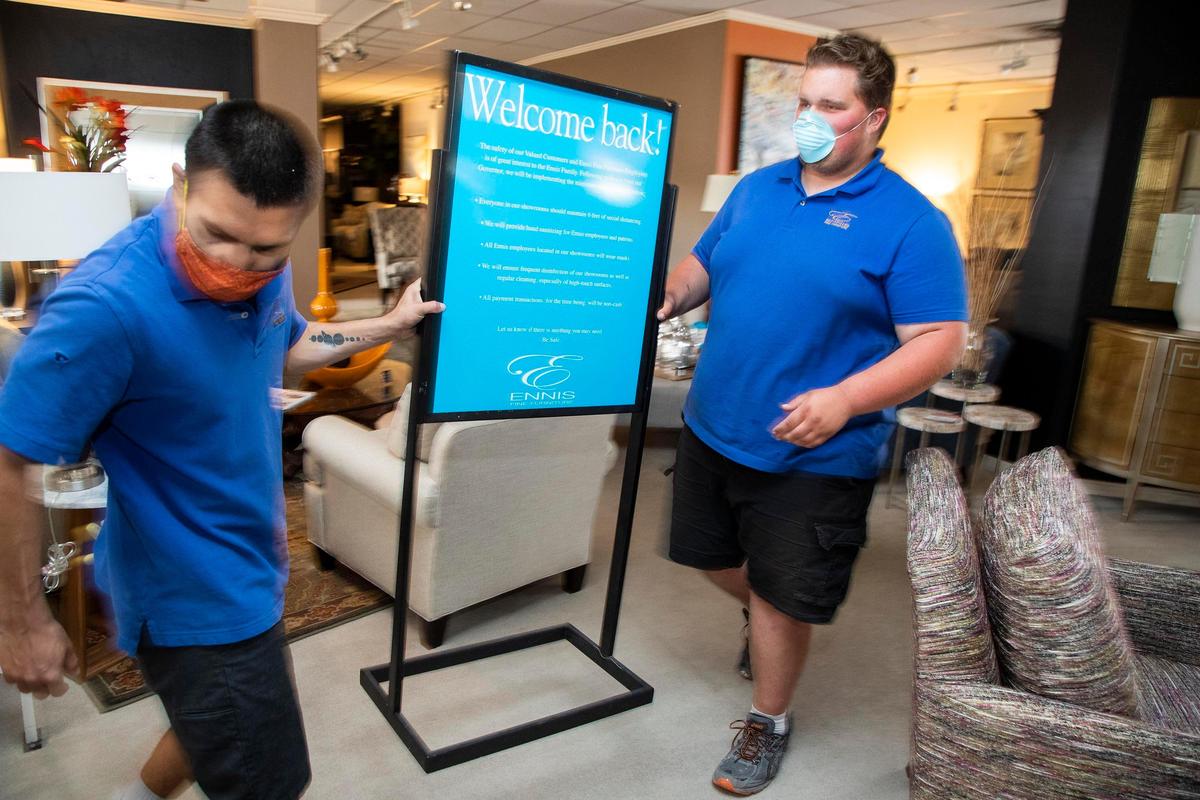 Ennis Fine Furniture employees Tobias Sherman, Jr. and Corbin Broner, right, place “Welcome back!” signs on the display floors of the Boise store.
