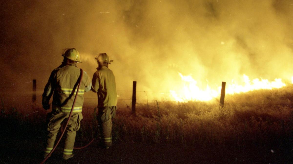 Firefighters try to stop flames from crossing a road near Cloverdale Road outside Kuna Friday night, July 28, 1995. Two Kuna firefighters died in the Point Fire.