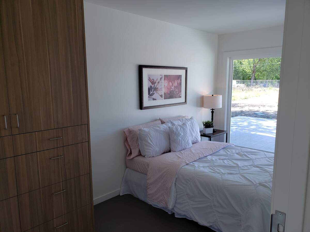The master bedroom at one of the original Windy Court homes features a large picture window that looks out of the front of the house and cabinets. The Windy Court 2 homes look similar.