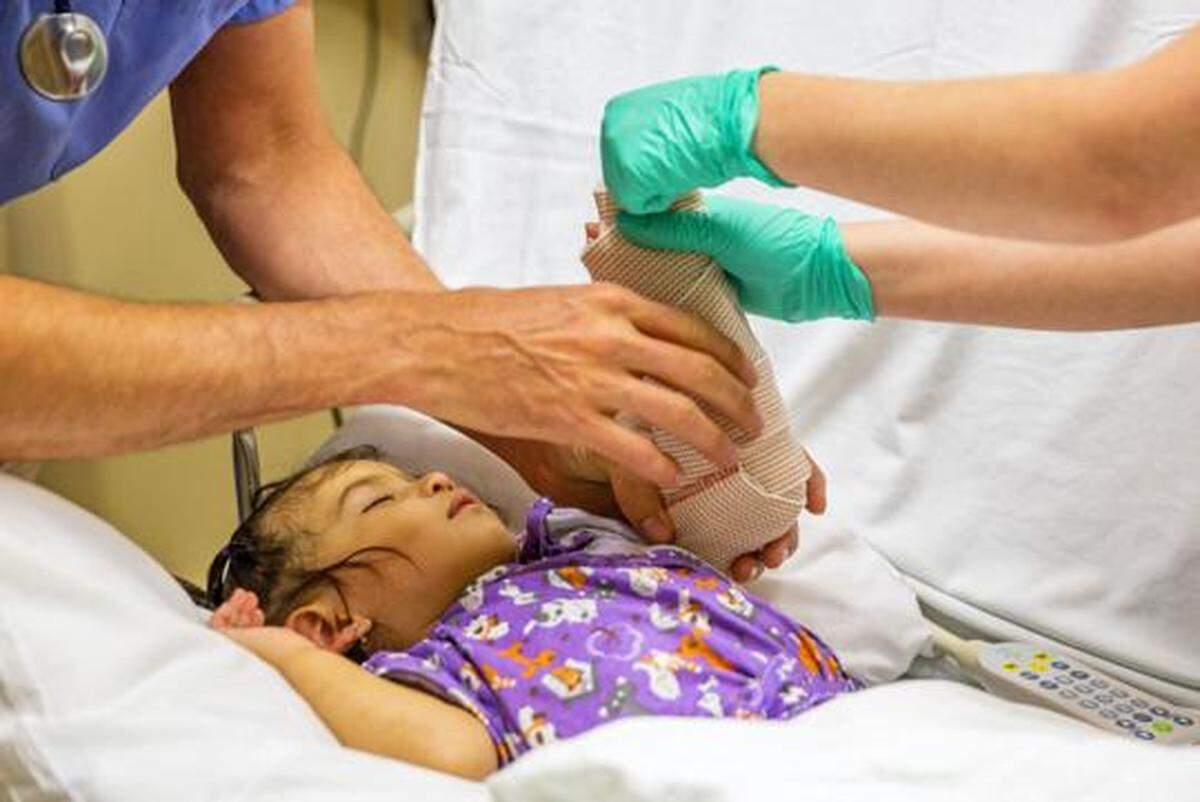 Dr. John Hanowell, left, and Certified Nursing Assistant Molly Veenstra prepare an arm sling for 15-month-old Amayrani Yescas Damas before her broken arm can be put into a cast July 6 at St. Luke’s Magic Valley Medical Center emergency room in Twin Falls.