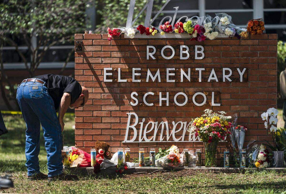 A law enforcement member lights a candle outside Robb Elementary School in Uvalde, Texas, on Wednesday.